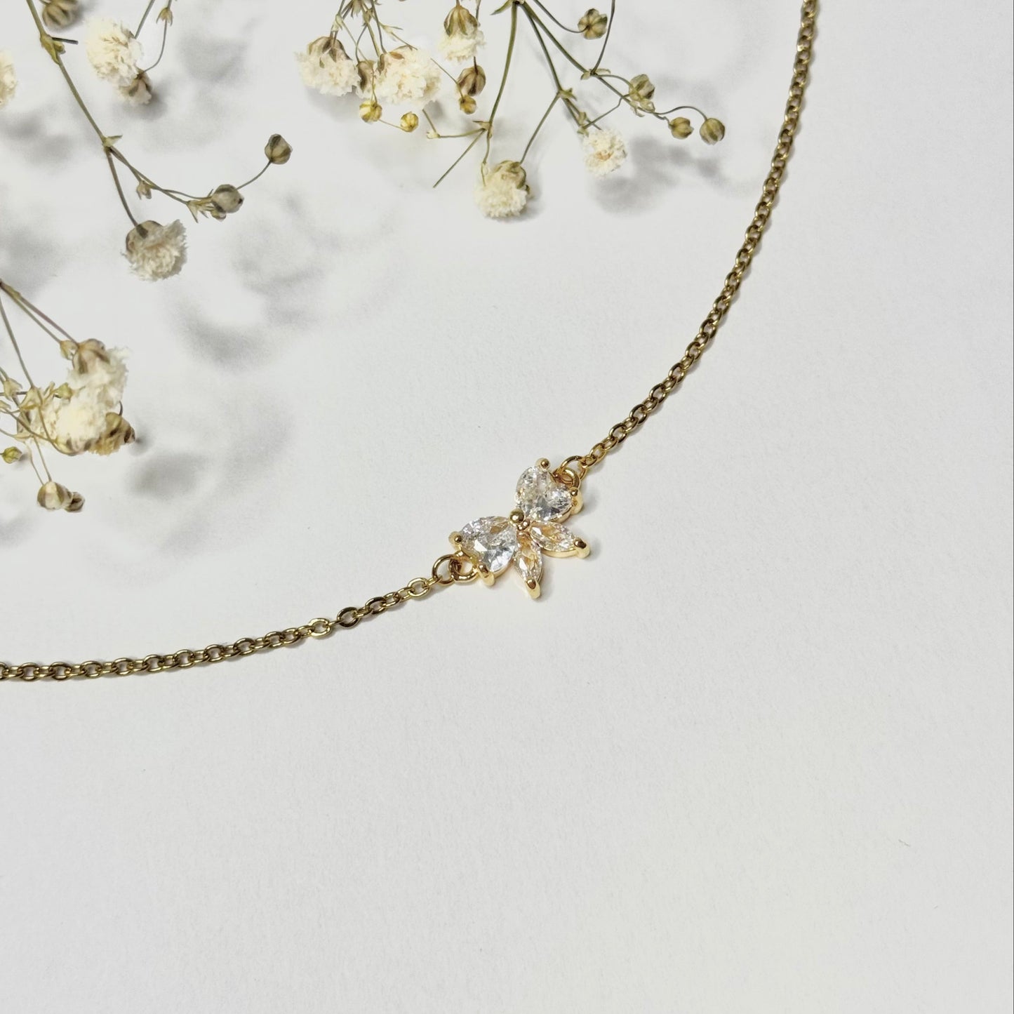 Collier doré en acier inoxydable et pendentif noeud en oxyde de zirconium fermoir mousqueton. Bijou élégant et minimaliste